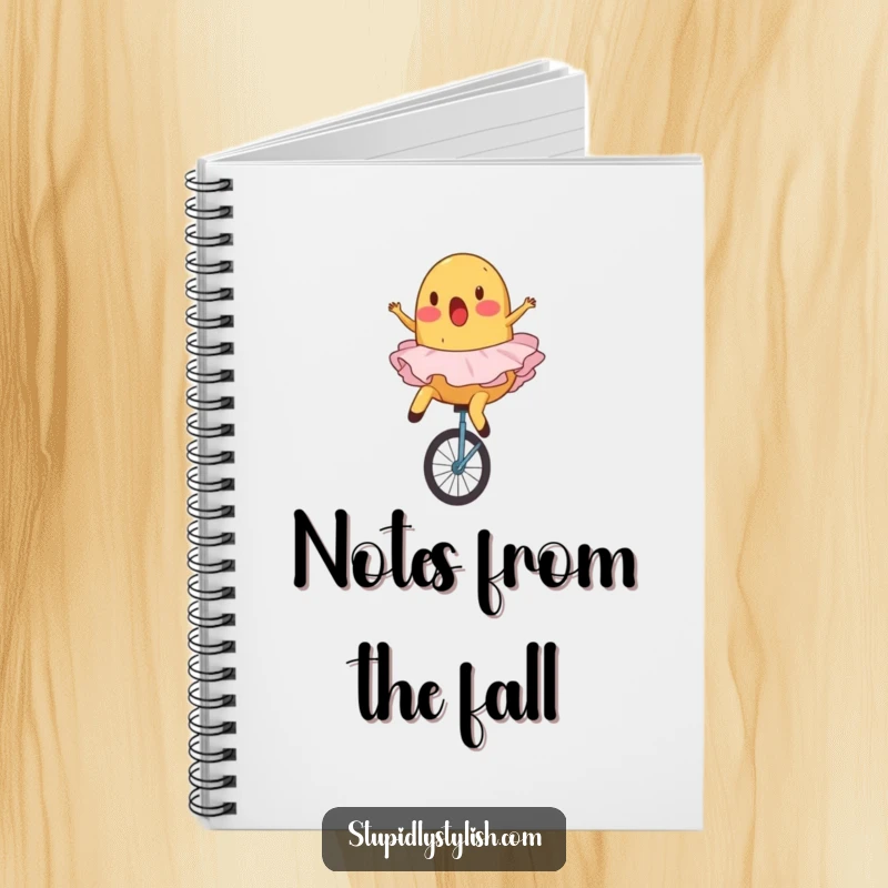 Funny, ruled notebook featuring a surprised potato in a ballet tutu comically falling off a unicycle.
