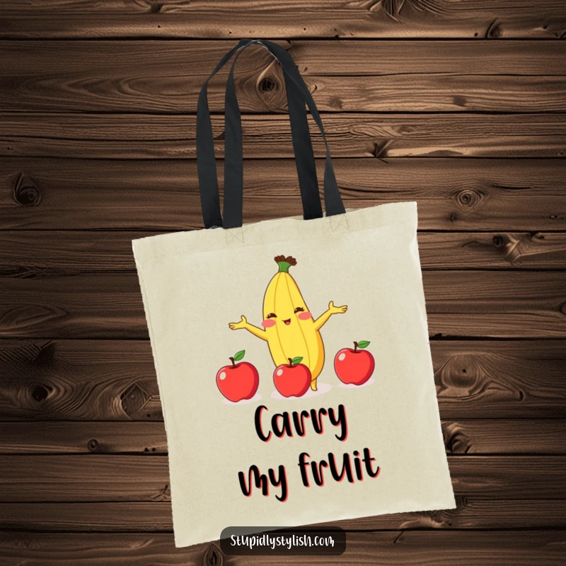 Funny tote bag featuring a blushing banana attempting to juggle three apples, adding a touch of quirky humor to your carry-all.
